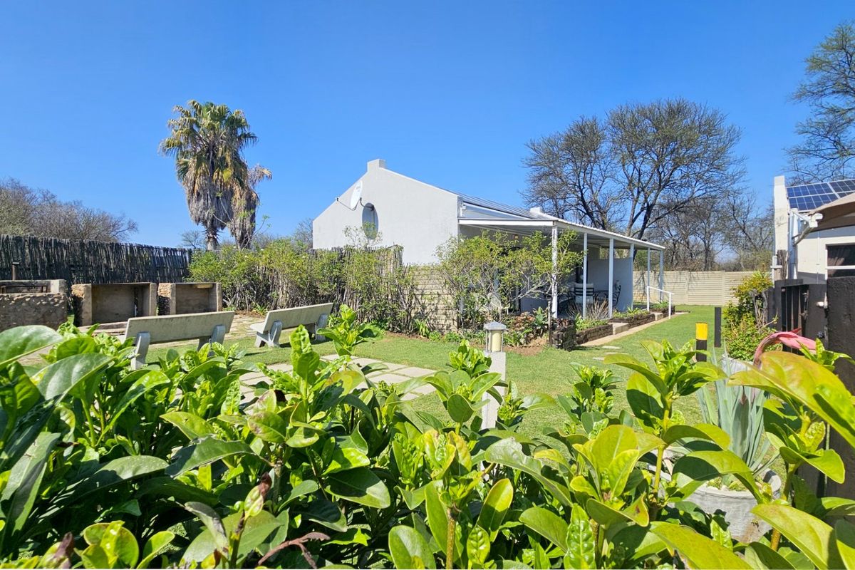 Rear exterior view featuring a covered patio, built-in braai area, landscaped garden, and solar panels installed on the roof.