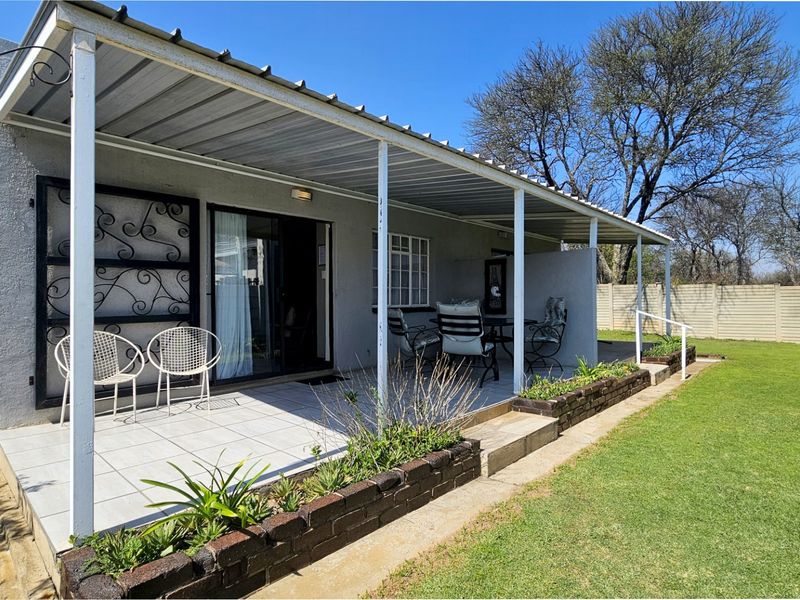 A covered outdoor patio area featuring tiled flooring, brick planter boxes, and direct access to the garden through sliding glass doors.