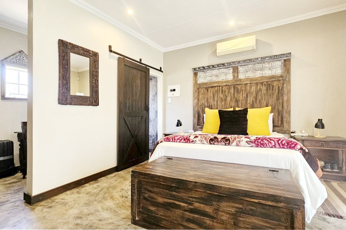 A well-maintained bedroom featuring polished concrete floors, a rustic sliding barn door, and a wall-mounted air conditioning unit.