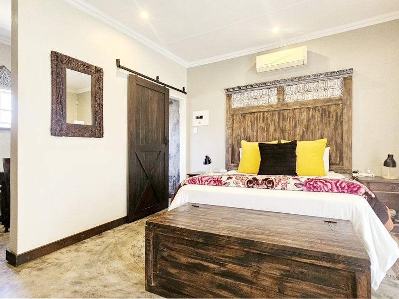 A well-maintained bedroom featuring polished concrete floors, a rustic sliding barn door, and a wall-mounted air conditioning unit.