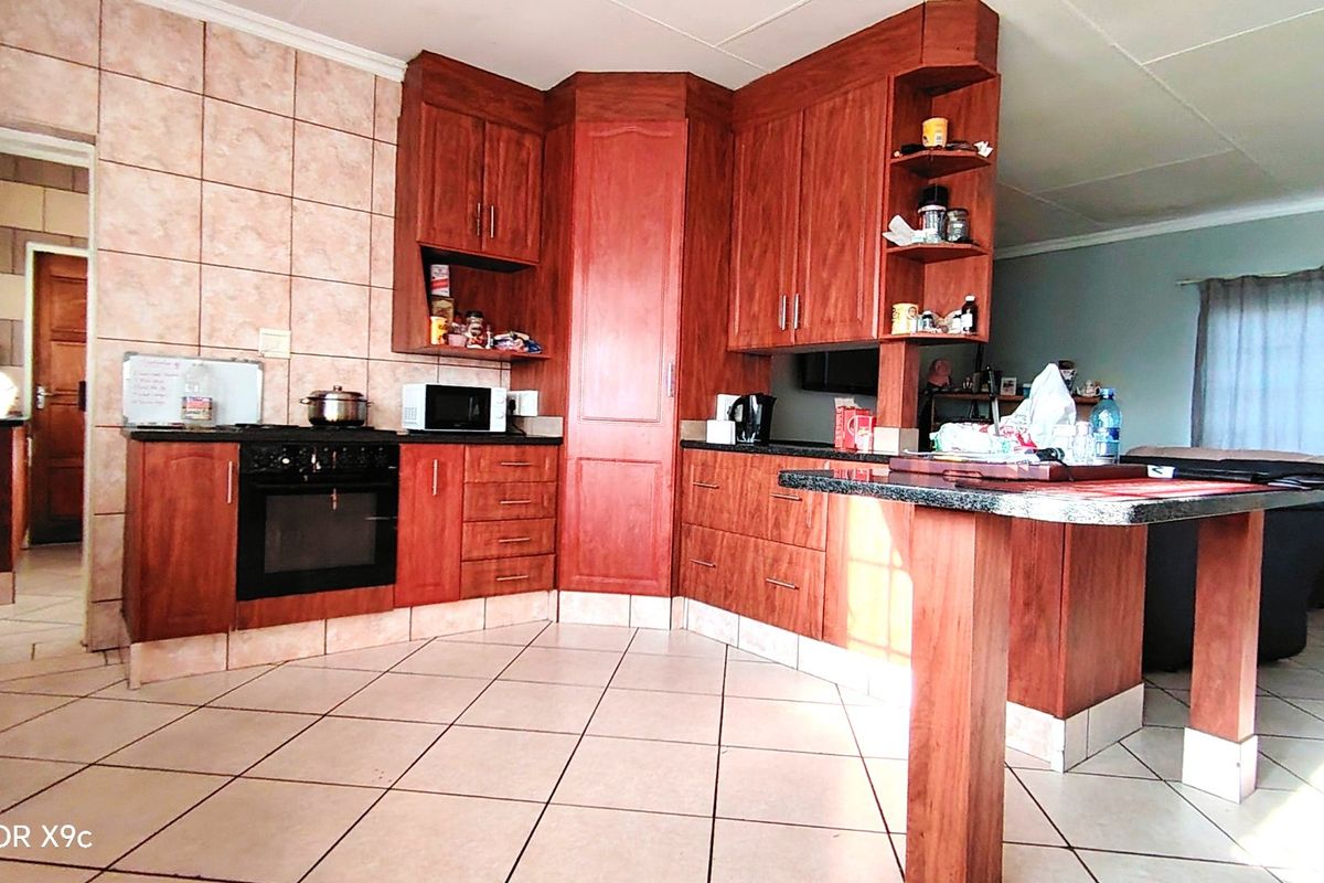 A functional kitchen featuring warm-toned wooden cabinetry, granite countertops, a built-in oven, and a breakfast nook, finished with tiled flooring and backsplash.