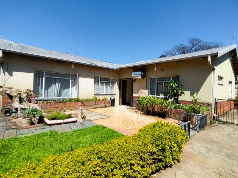 Rear exterior view of the house featuring a tiled patio area, brick planter boxes, and a solar water heater installation.