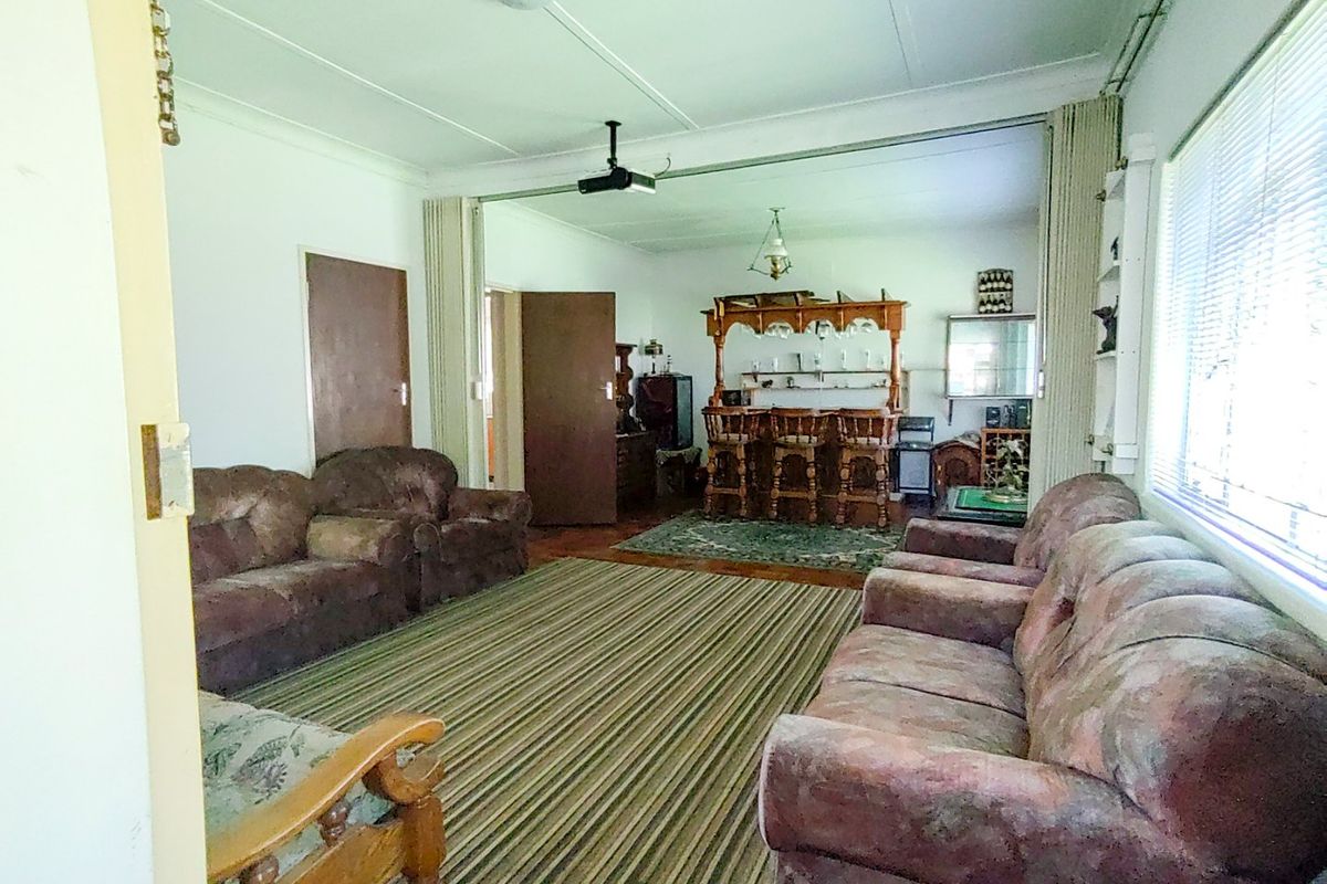 Spacious living area featuring a built-in bar, sliding room divider, and ceiling fan, offering potential for modernization and open-plan living.