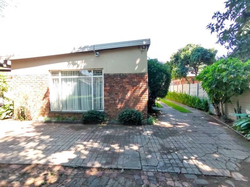 Exterior view of the property featuring a brick facade, paved driveway, and secure boundary walling.