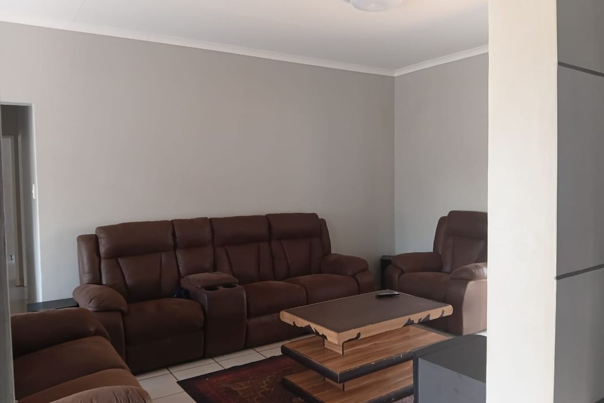 A neutrally painted living room featuring tiled flooring and a central ceiling light fixture, offering a clean and functional space.