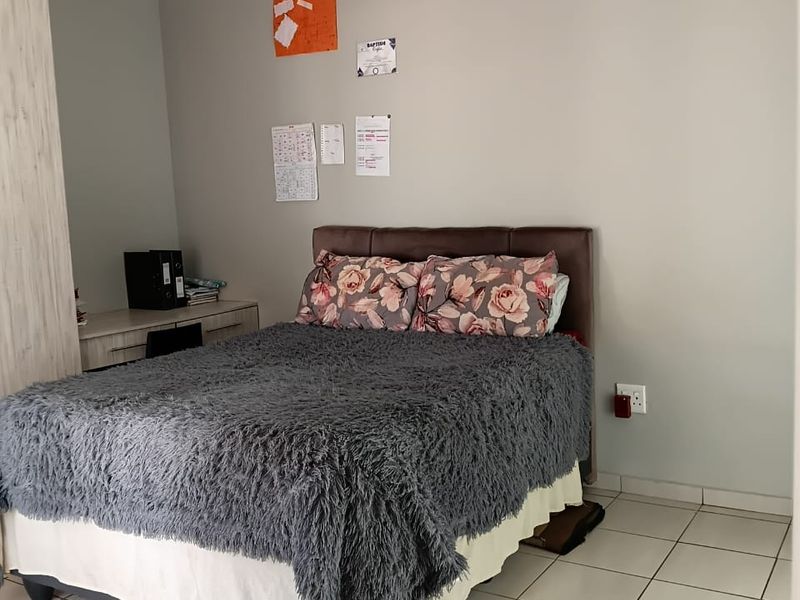 A functional bedroom featuring tiled flooring, a built-in wardrobe, and neutral wall finishes, providing a clean and practical living space.