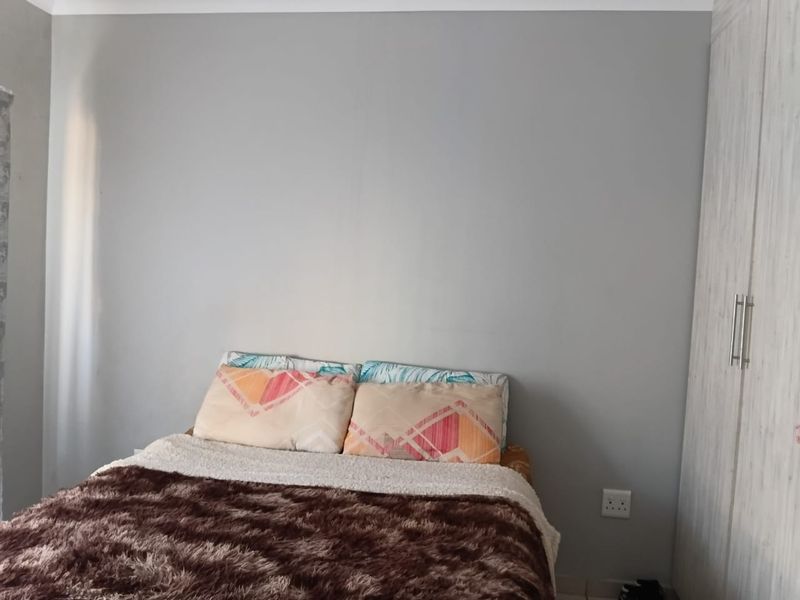 A bedroom featuring neutral grey walls and a built-in wardrobe with modern handles.