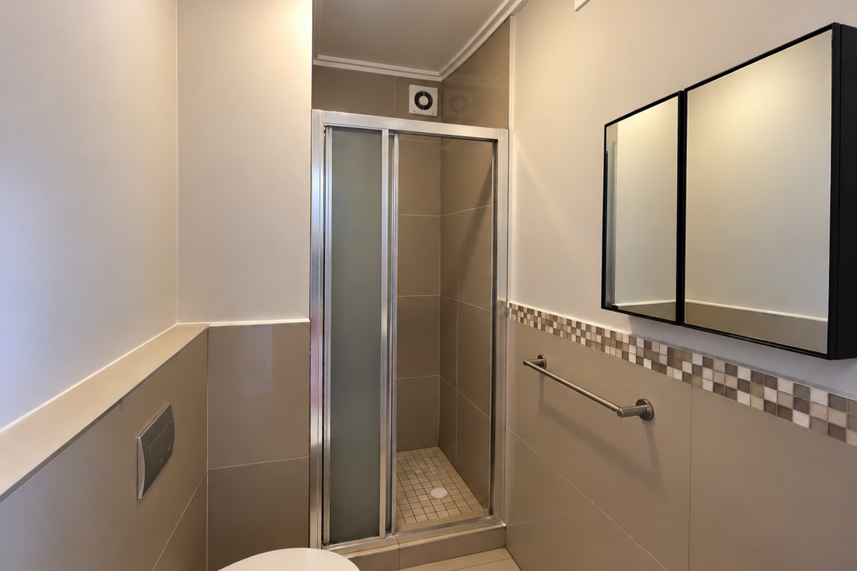 Modern bathroom featuring a glass-enclosed shower, wall-mounted toilet, neutral tiled finishes, and a sleek medicine cabinet with a decorative mosaic tile border.