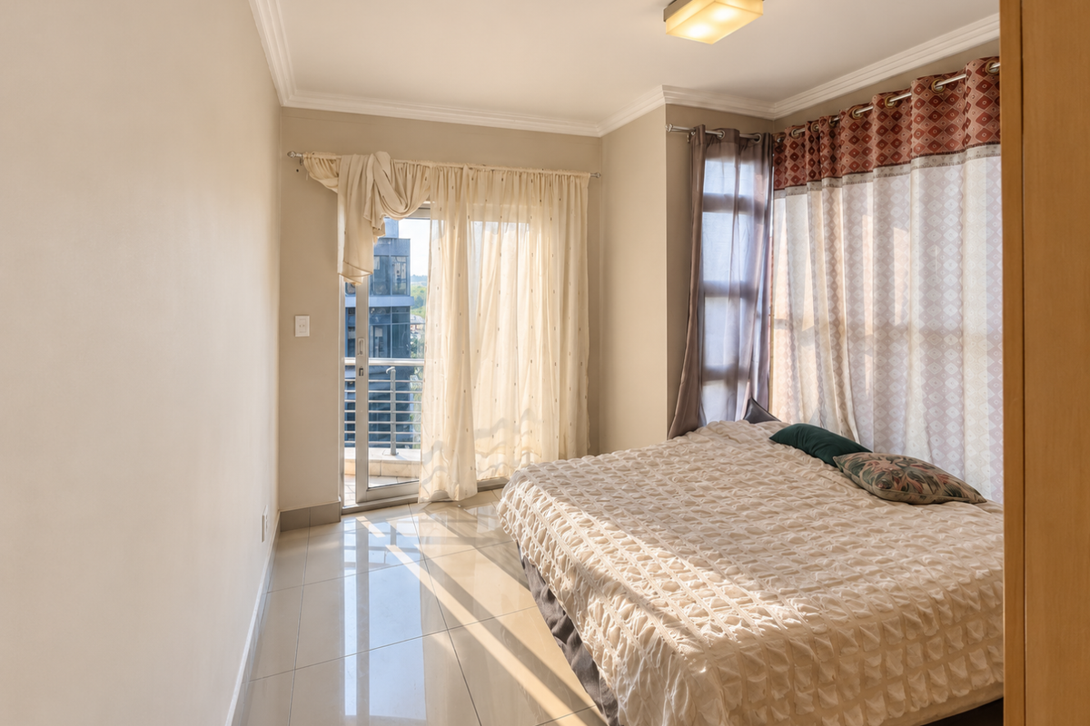 Bright bedroom featuring tiled flooring, ceiling lighting, and direct access to a private balcony through a sliding glass door.