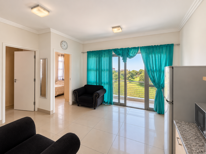 Open-plan living area featuring tiled floors, modern kitchen cabinetry with granite countertops, and large sliding doors leading to a balcony with scenic views.