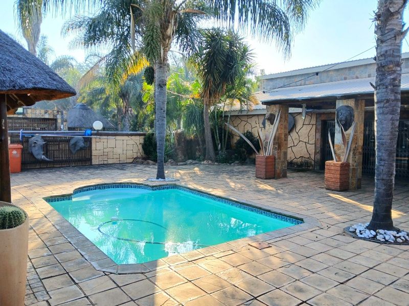 Outdoor pool area featuring a swimming pool, paved patio, and a thatched lapa, providing a functional space for outdoor entertainment.