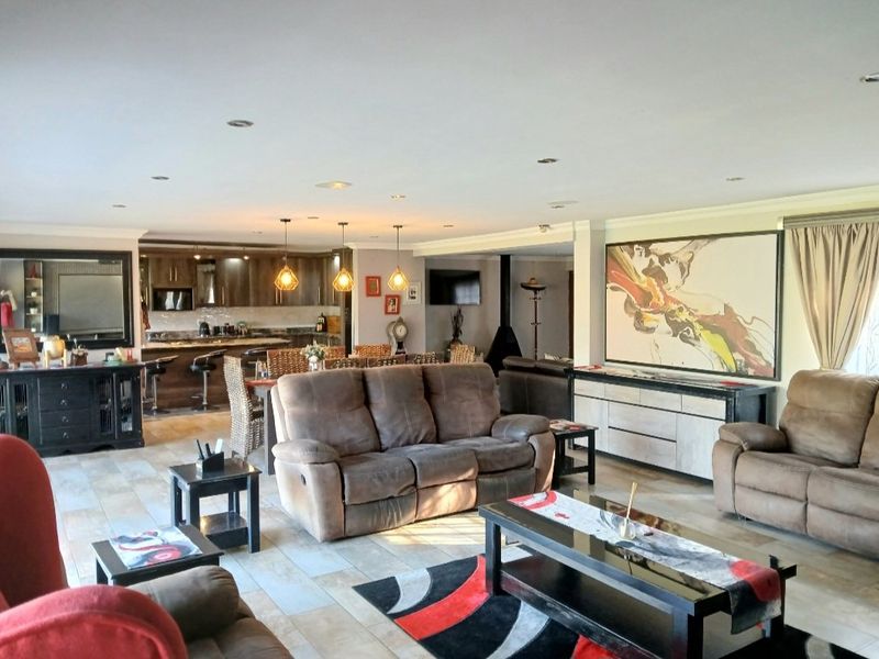 Spacious open-plan living area featuring a modern kitchen with island, tiled flooring, and a cozy fireplace, creating a seamless flow for entertaining.