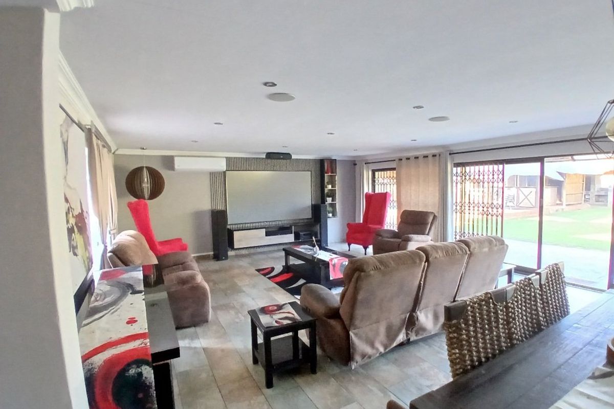 Spacious living room featuring tiled flooring, recessed lighting, a built-in media wall, and large sliding glass doors providing access to the garden.