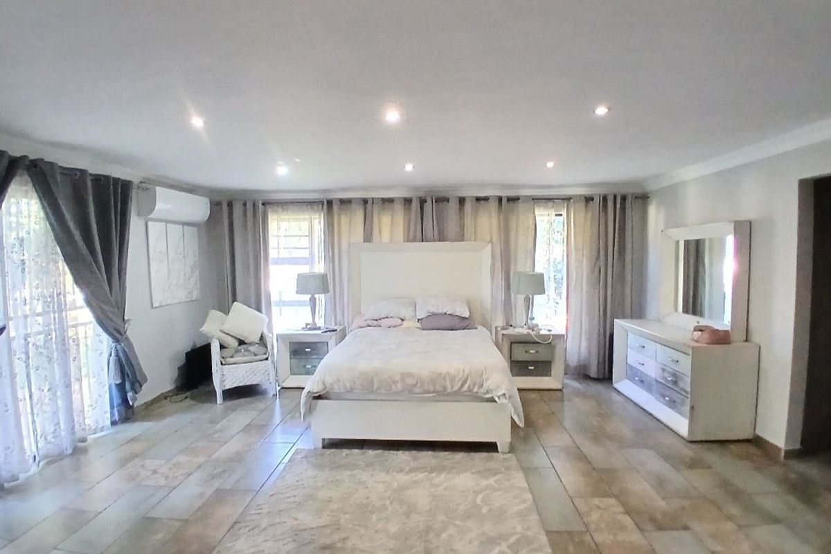 Spacious bedroom featuring tiled flooring, recessed downlighting, and a wall-mounted split-system air conditioning unit.
