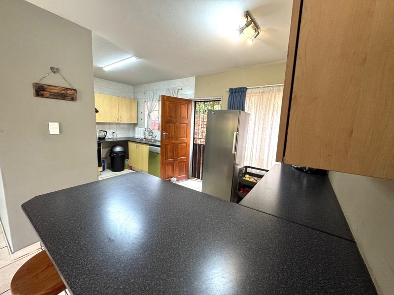 Functional kitchen featuring laminate cabinetry, dark countertops, and direct access to the exterior via a security gate.