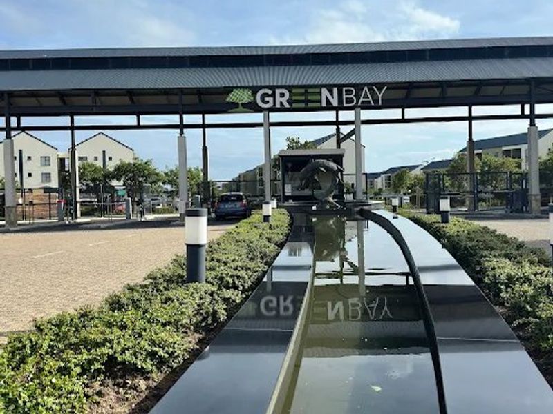 The main entrance to the Greenbay estate featuring a modern gated access point, a decorative water feature, and well-maintained landscaped surroundings.