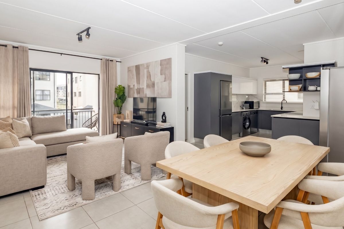 Modern open-plan living area featuring a contemporary kitchen with sleek cabinetry, tiled floors, and seamless flow to a private balcony.