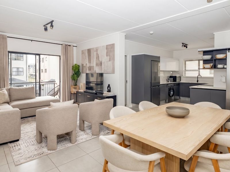 Modern open-plan living area featuring a contemporary kitchen with sleek cabinetry, tiled floors, and seamless flow to a private balcony.