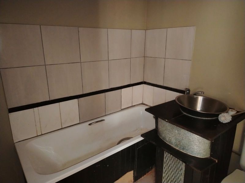 A bathroom featuring a standard bathtub with tiled splashback and a unique vessel sink vanity unit.