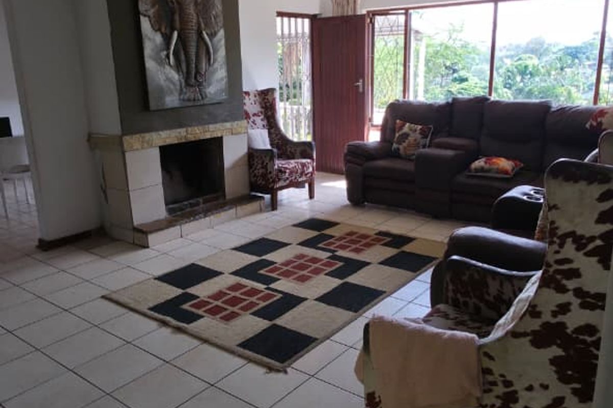 Spacious living room featuring tiled flooring, a central fireplace, and large sliding glass doors that provide natural light and outdoor access.