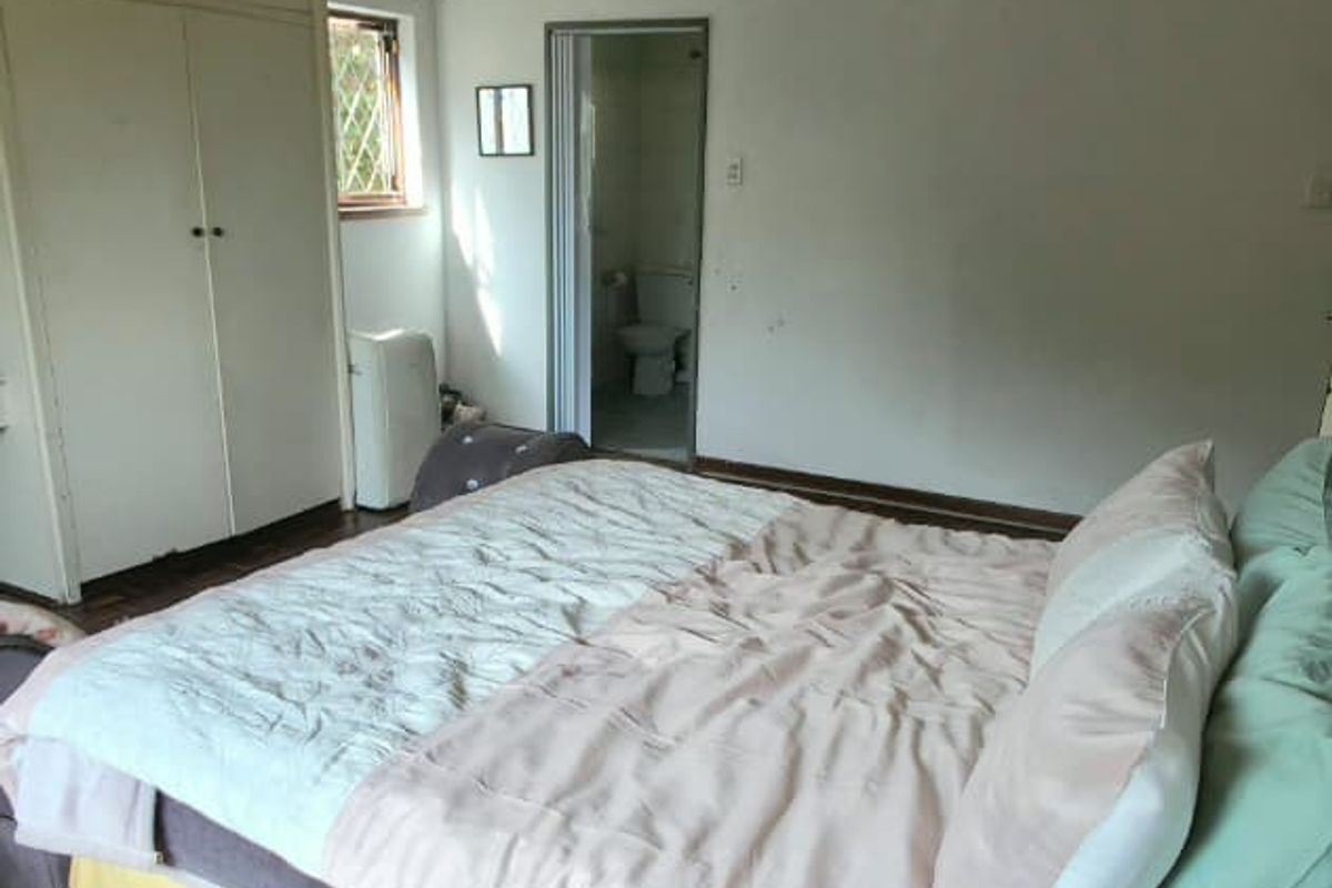 Bedroom featuring parquet flooring, built-in cupboards, and a ceiling fan, with direct access to an en-suite bathroom.