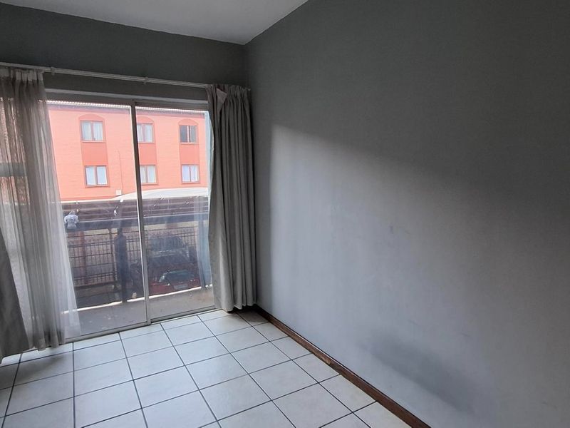 An empty bedroom featuring tiled flooring and a sliding glass door providing access to an outdoor area.