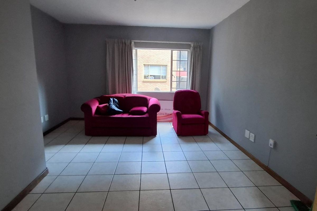 A simple living room featuring neutral grey walls and light-colored tiled flooring, providing a blank canvas for interior design.
