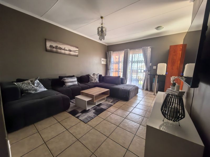 A living room featuring ceramic tile flooring, a coved ceiling, and a sliding glass door with a security gate leading to the exterior.