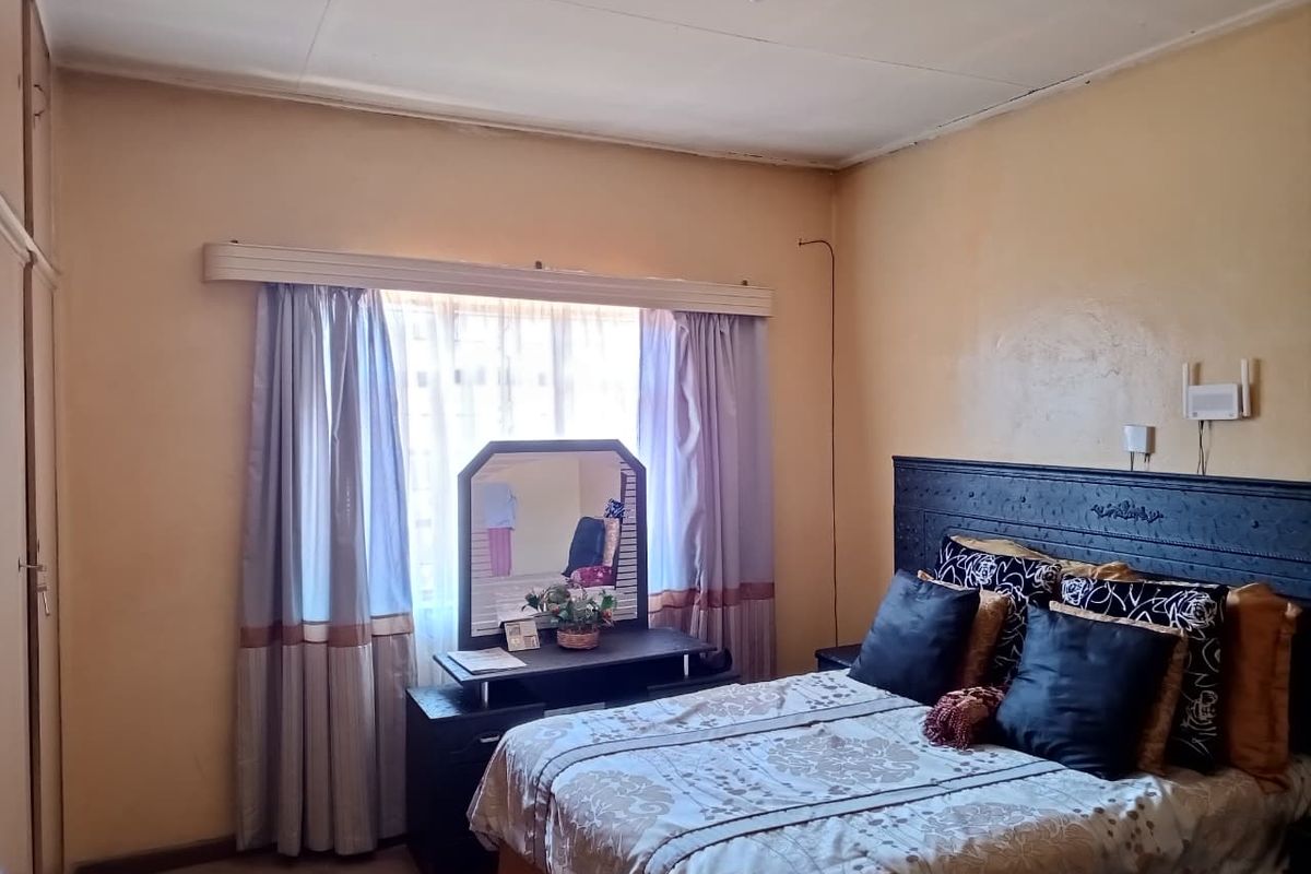 A bedroom featuring a built-in wardrobe and a window with curtain rails, requiring cosmetic updates to the walls and ceiling.