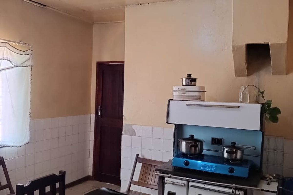A dated kitchen featuring a built-in stove, extractor hood, and tiled splashback, offering potential for modernization and renovation.