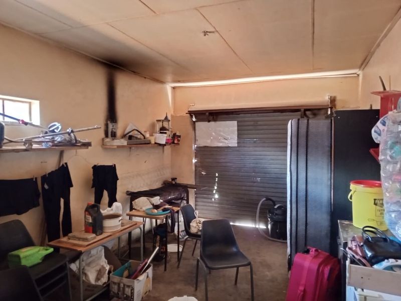 A functional garage space featuring a roller shutter door and built-in shelving, showing signs of wear and surface staining on the walls.