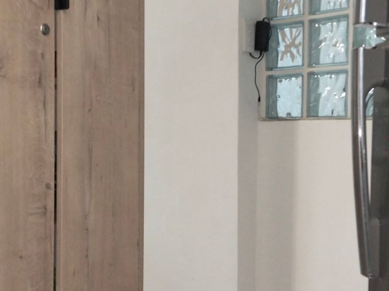 A view of a kitchen area featuring light wood-look cabinetry, tiled flooring, and a decorative glass block window.