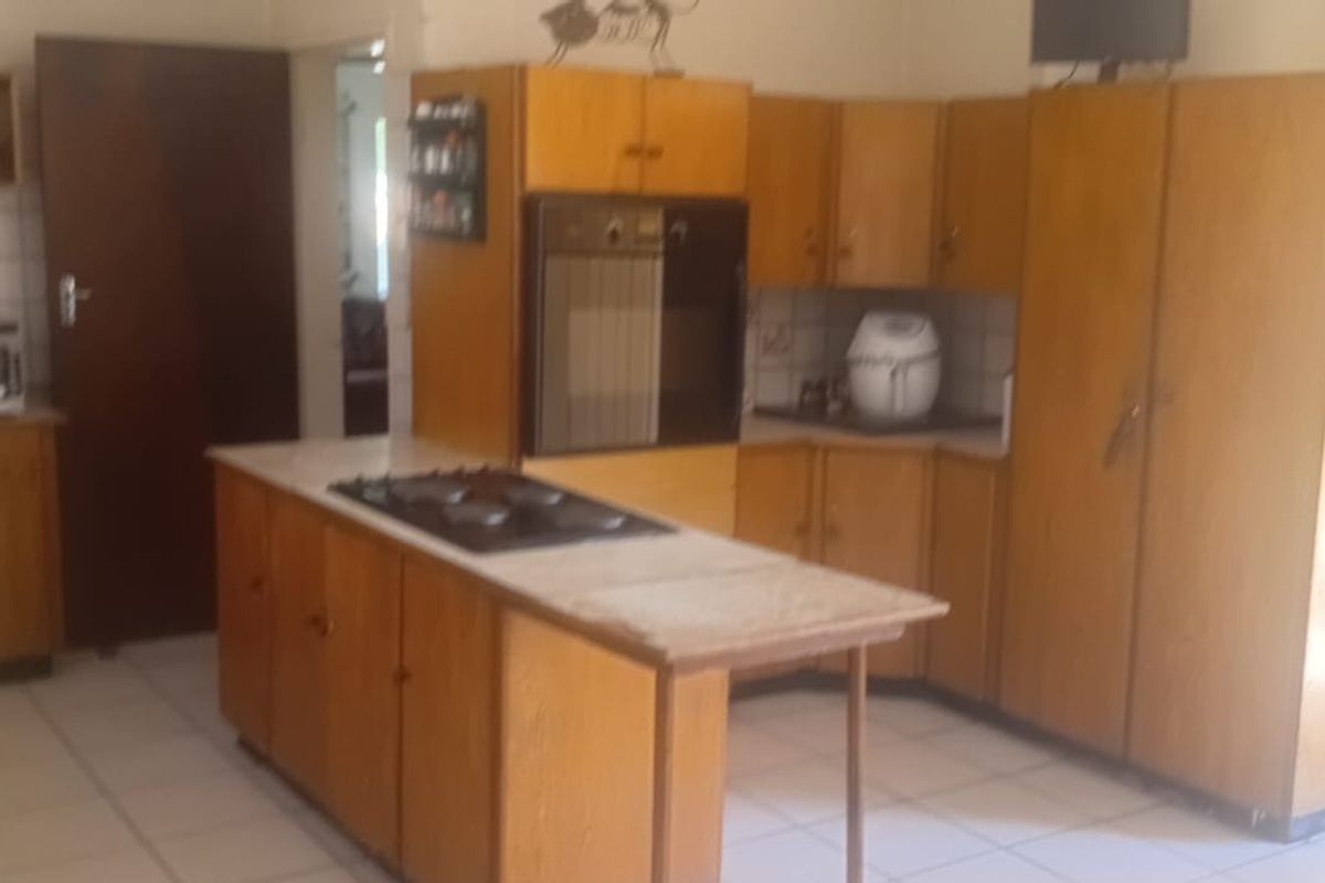 A dated kitchen featuring wooden cabinetry, a built-in oven, a hob, and tiled flooring, offering significant potential for a modern renovation.