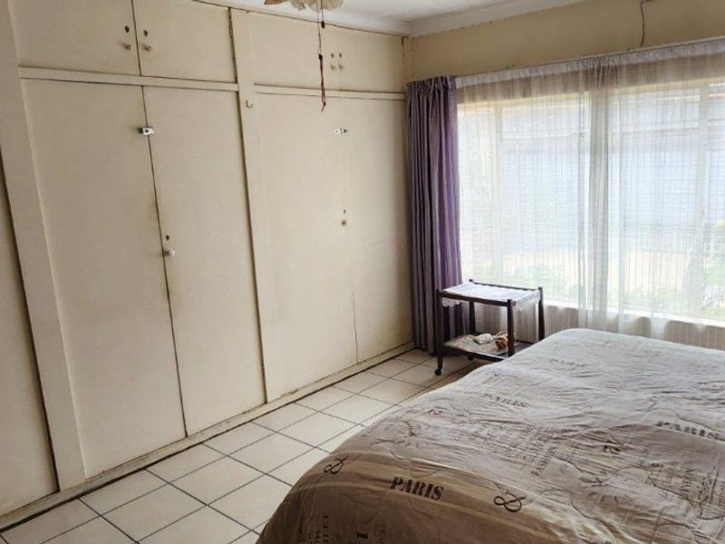 Bedroom featuring tiled flooring, a large window for natural light, and extensive built-in cupboard storage.