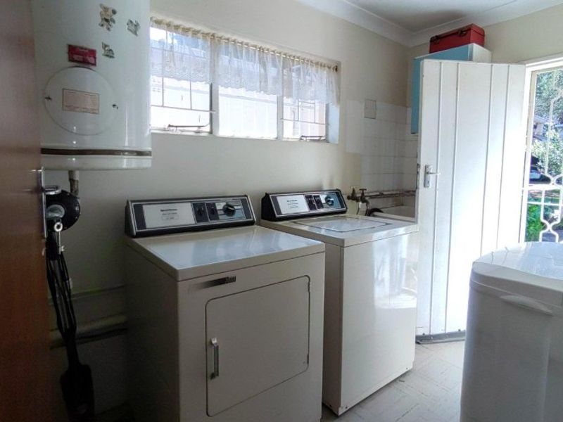 Functional laundry room featuring a wall-mounted geyser, utility sink, and direct access to the exterior via a security gate.