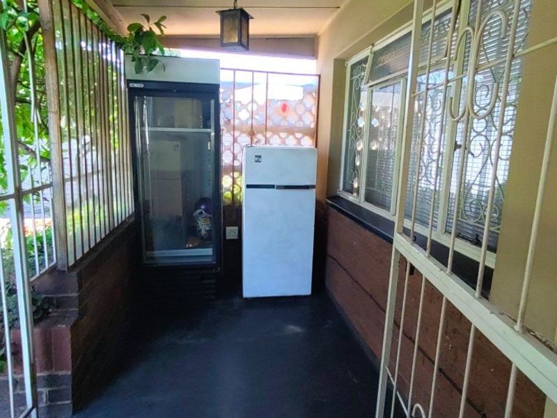 A covered patio area featuring security gates and bars, providing a functional outdoor space with potential for enhancement.