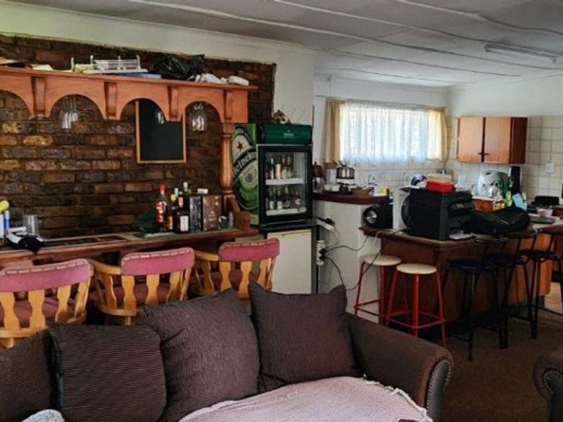 Open-plan living area featuring a rustic exposed brick bar, integrated kitchen cabinetry, and a breakfast counter, offering a functional and versatile layout.
