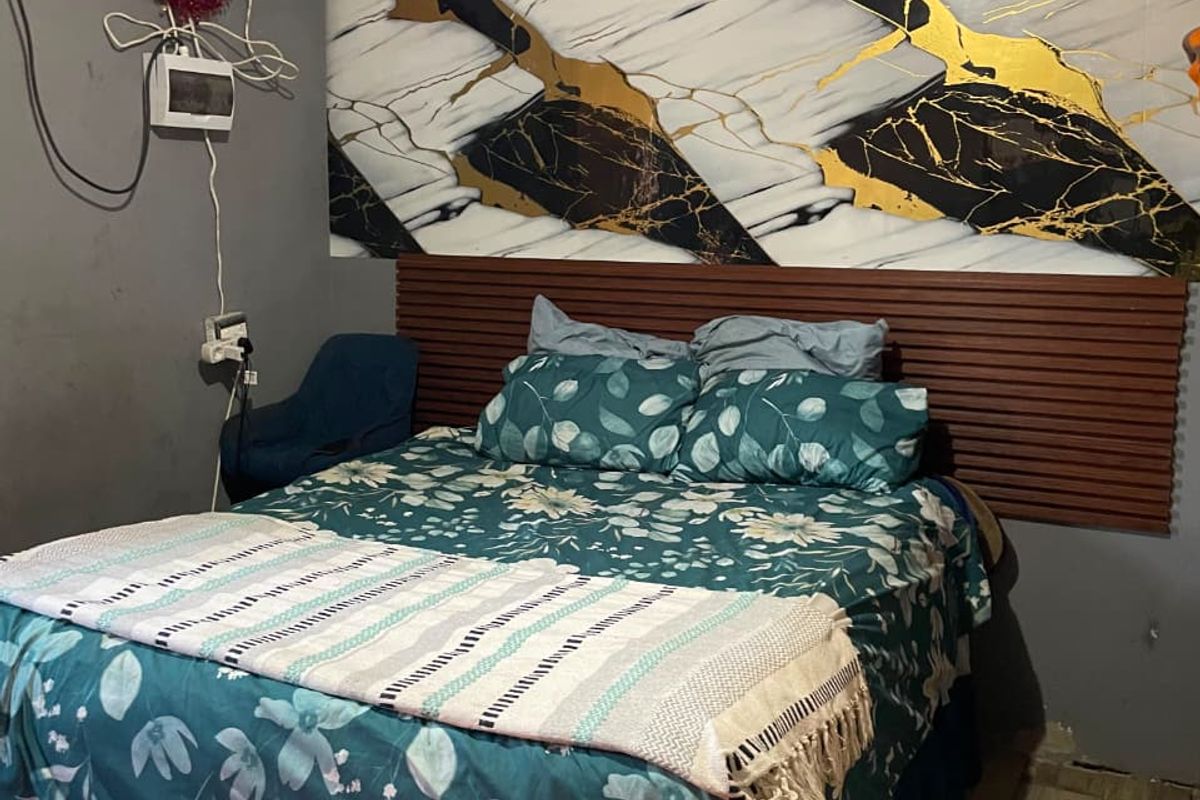 Bedroom featuring a decorative marble-effect wall panel, wood slat headboard, and tiled flooring, requiring attention to exposed electrical wiring and wall finishes.