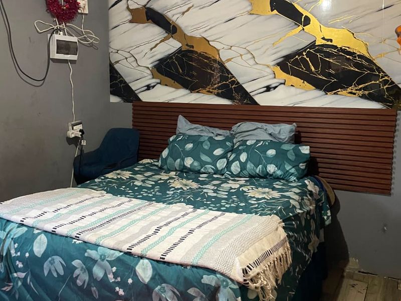 Bedroom featuring a decorative marble-effect wall panel, wood slat headboard, and tiled flooring, requiring attention to exposed electrical wiring and wall finishes.