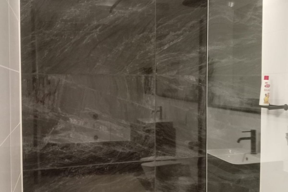 Modern bathroom featuring a spacious walk-in shower with a glass screen, rain shower head, and elegant dark marble-effect wall tiling.
