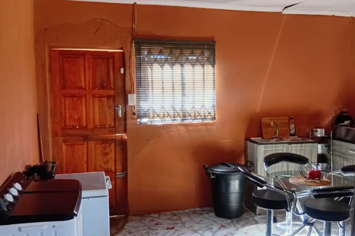 A functional kitchen area featuring built-in cabinetry, a sink, and a timber door, currently showing signs of wear and requiring cosmetic updates.