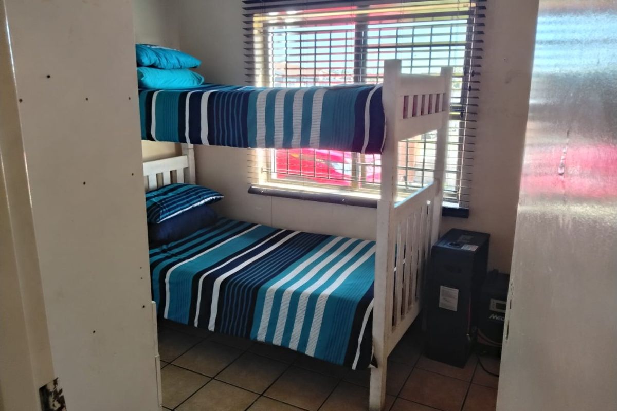A compact bedroom featuring tiled flooring and a window with fitted venetian blinds.