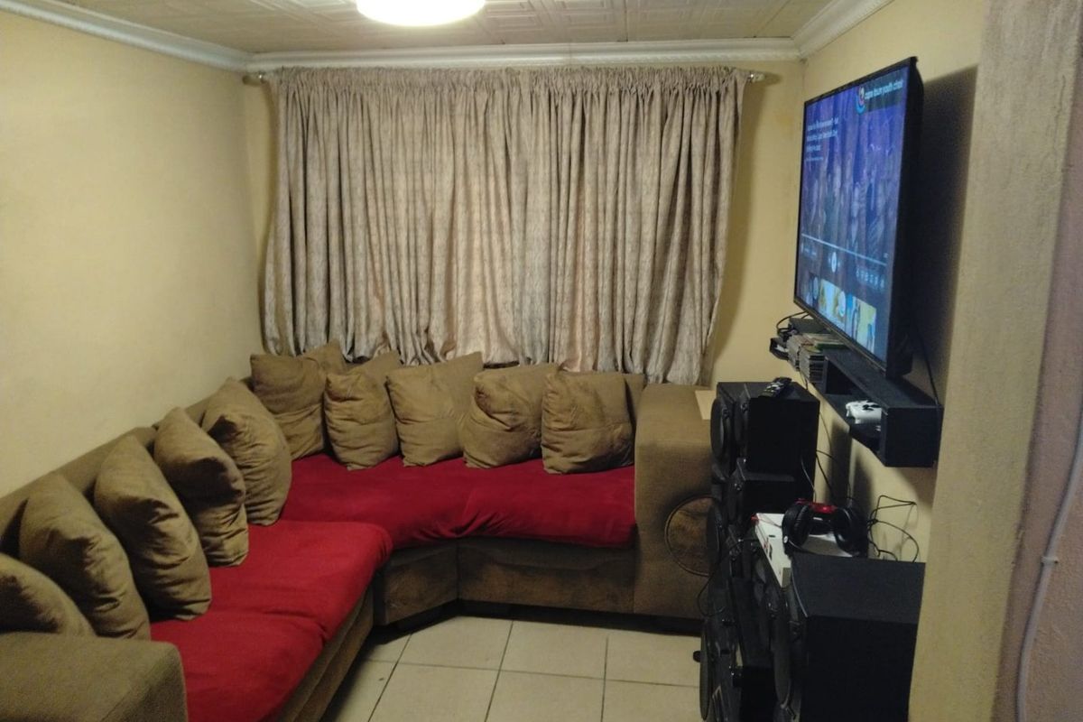 A compact living room featuring tiled flooring and a textured ceiling, currently set up as a media space.