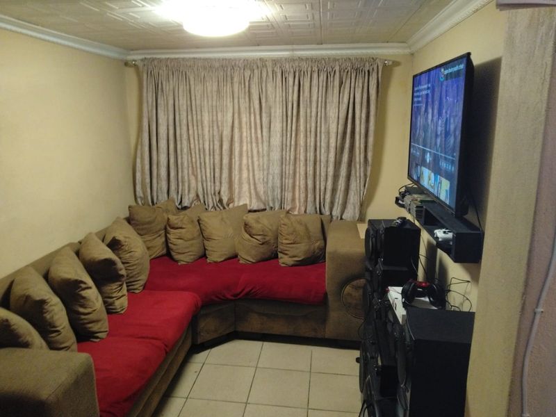 A compact living room featuring tiled flooring and a textured ceiling, currently set up as a media space.