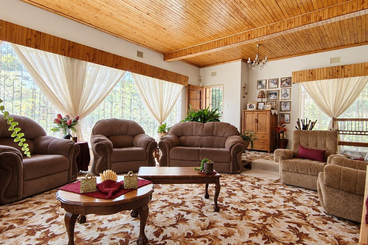 Spacious living room featuring a warm timber tongue and groove ceiling, large windows with security gates, and patterned carpet flooring.