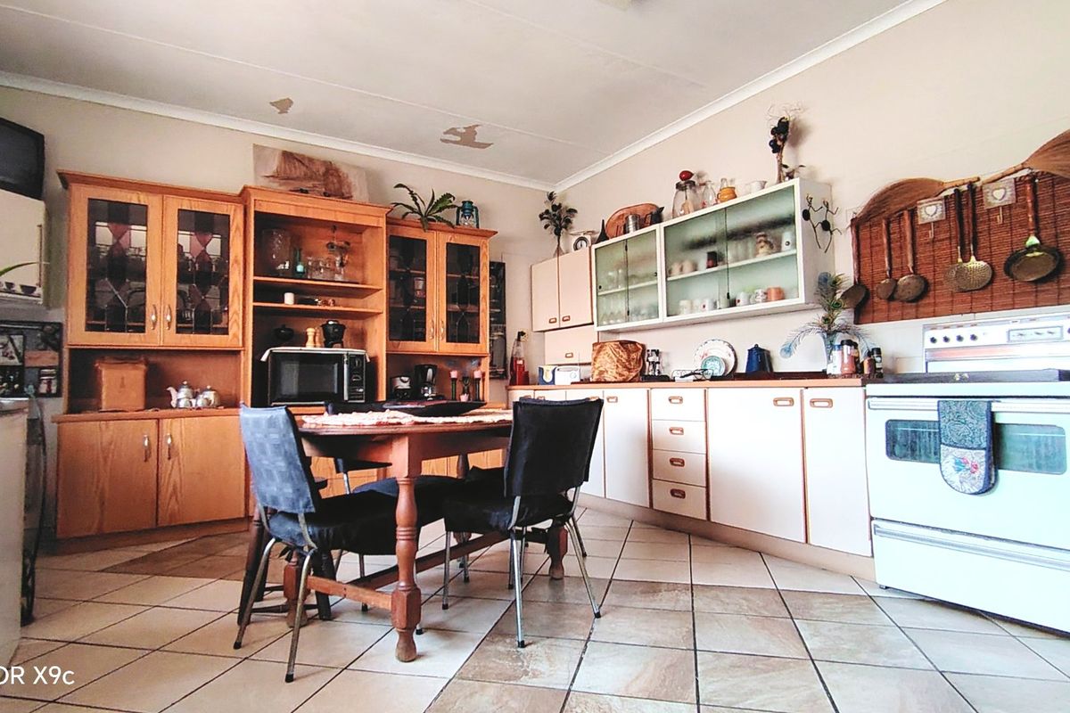 A dated kitchen featuring wooden cabinetry, tiled flooring, and a freestanding stove, offering potential for modernization and renovation.