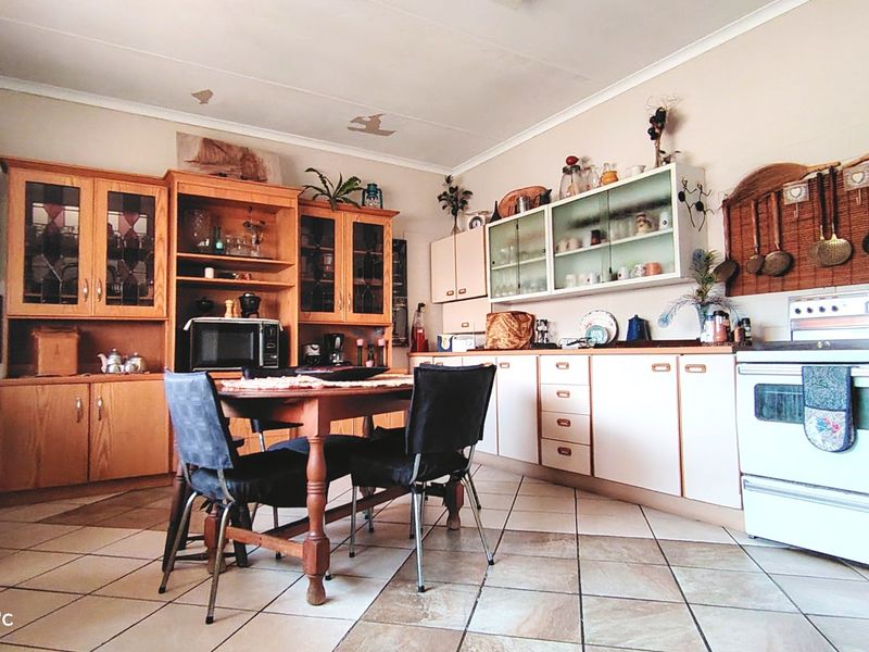 A dated kitchen featuring wooden cabinetry, tiled flooring, and a freestanding stove, offering potential for modernization and renovation.