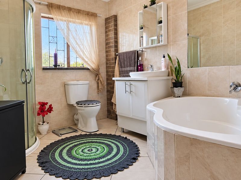 A well-maintained bathroom featuring a corner shower enclosure, a built-in bathtub, a vanity unit with basin, and neutral wall tiling.