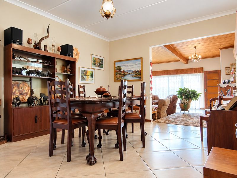 Open plan dining and living area featuring ceramic tiled flooring, timber ceiling beams, and a sliding glass door leading to the exterior.