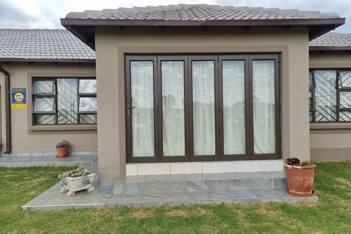 Rear exterior view featuring a tiled patio area with folding glass doors and secure window frames.